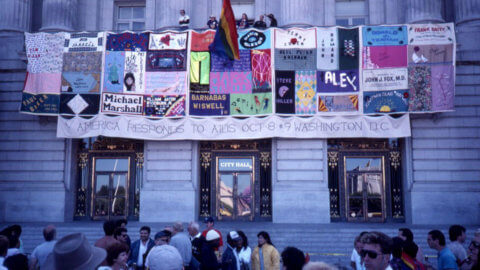 Fabric banners on San Francisco City Hall. The longest banner text reads "America Responds to AIDS Oct 8-9 Washington DC"