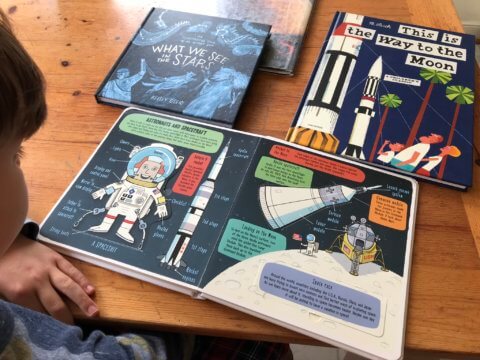 Child looking at books on space.