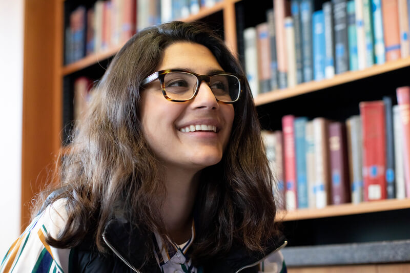 UCSF student in front of library bookshelf