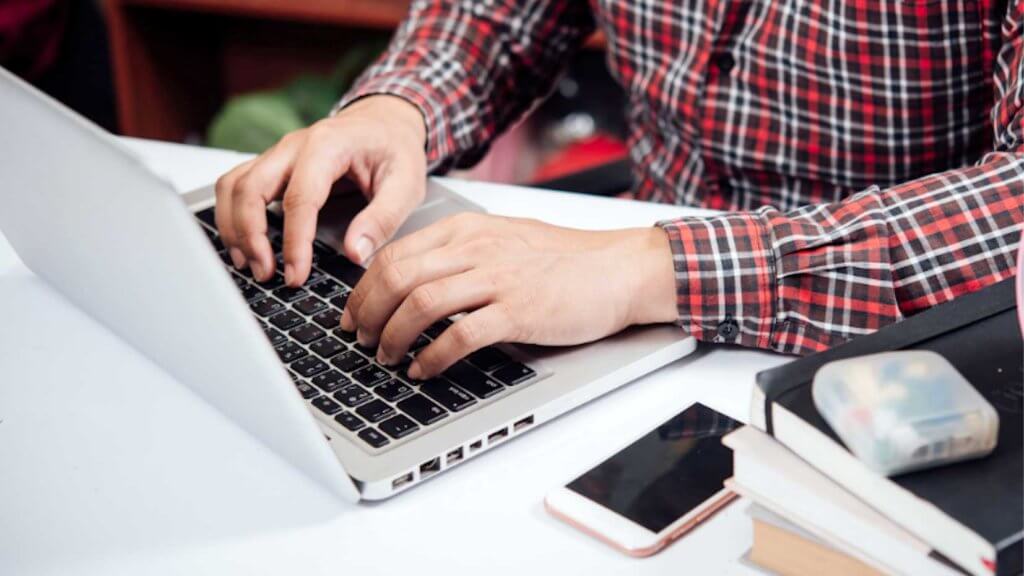 student typing on laptop