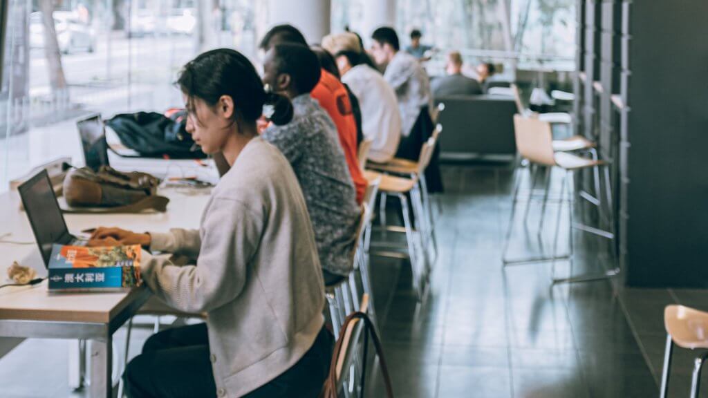 Group of people of different genders and races using their laptops.