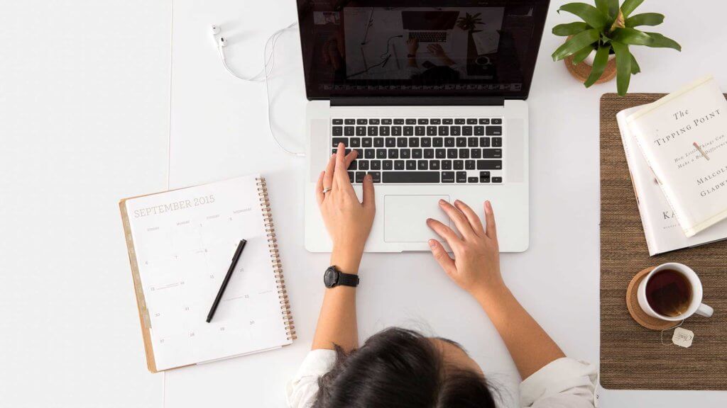 student with notebook, laptop, and coffee