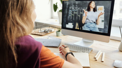 woman writing and watching computer