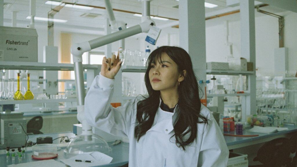 A scientist looking at a vial in a lab