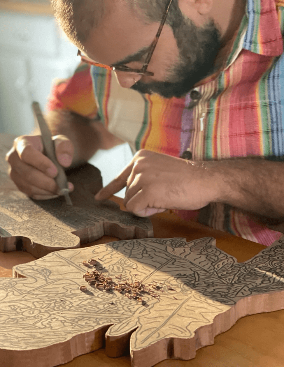 Jacoub Reyes carving a large woodcut in his studio.