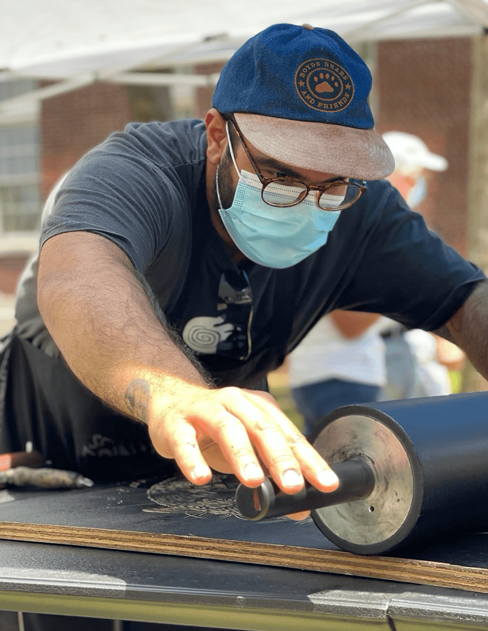 Jacoub Reyes inking his large woodblock during Seminole County Printmakers Steamroller Printing Event.