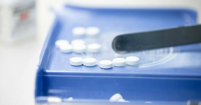 White buprenorphine tablets being sorted into a blue dish