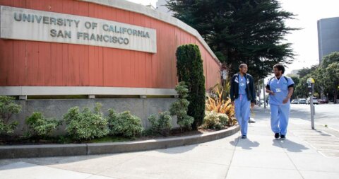 UCSF SOM students walking by the UCSF sign at Parnassus Heights