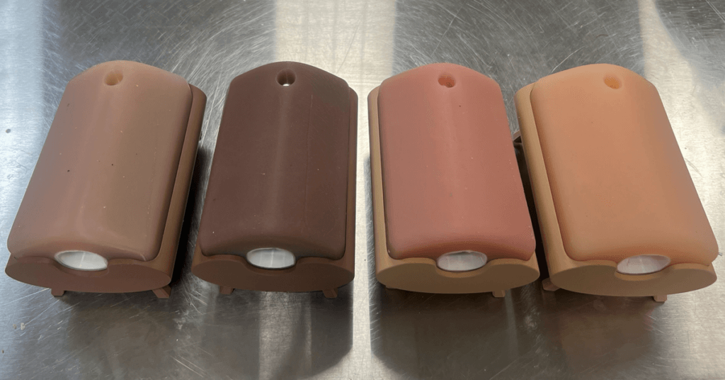 Four of Nina Patel's tracheostomy simulators in four different skin tone shades.