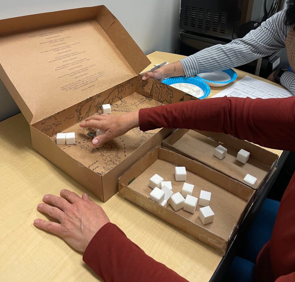 A hand reaching for rough and smooth white 3D printed cubes in experiment setup.
