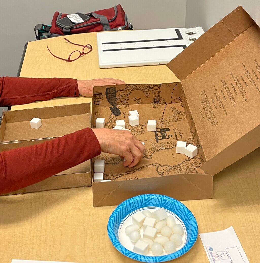 During an experiment, a patient sorts 3D printed cubes in cardboard box