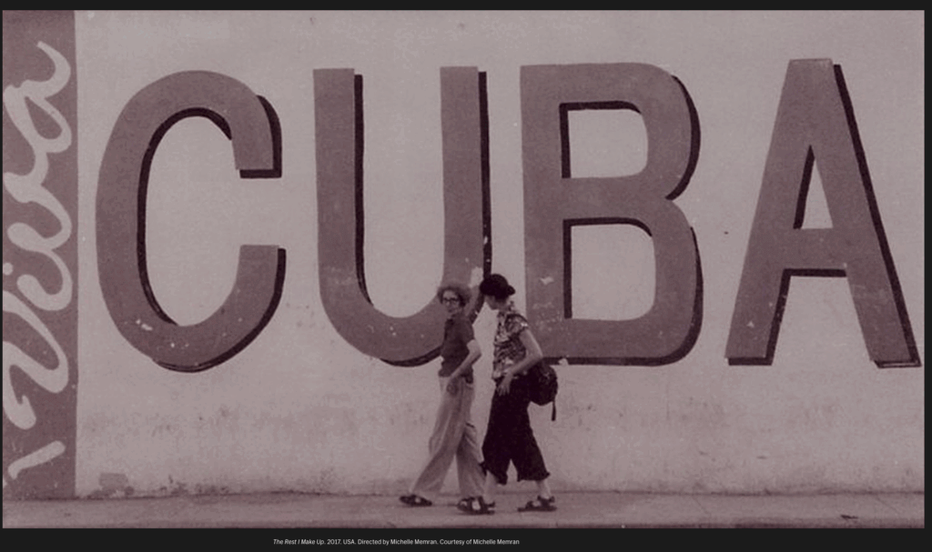 Still from the documentary, The Rest I Make Up, showing two people walking in front of a wall that has "Cuba" written on it.