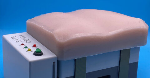 CPR traning device with flesh toned silicone on top and the device measuring rate and depth of compressions on the left side.