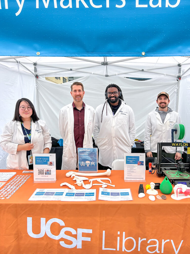 Tech Innovations team members Jenny Tai, Sean McClelland, Joshua Cobbet and Scott Drapeau standing at a booth to share information about the Makers Lab at the Bay Area Science Festival.
