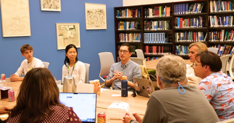 Group of people seated around a table having a discussion in the FAMRI Library
