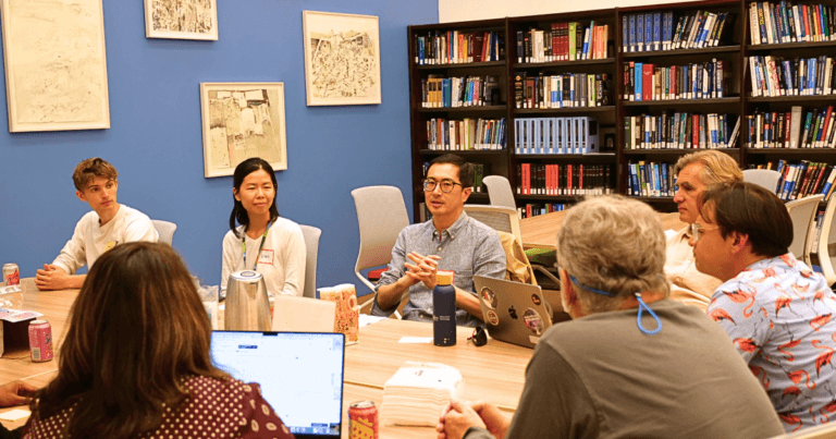 Group of people seated around a table having a discussion in the FAMRI Library