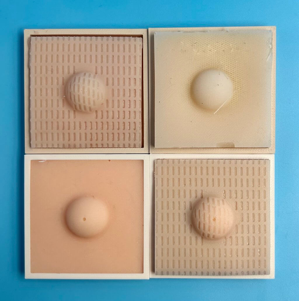 Top-down view of 4 silicone cyst model squares in various skin colors and textures.